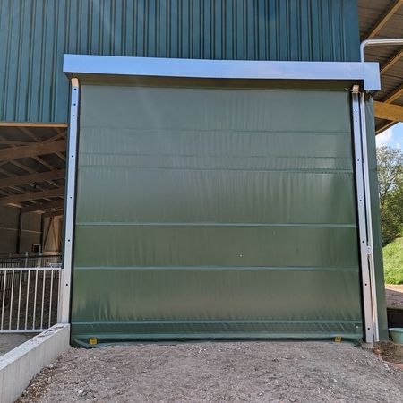 Ein grüner Stall der durch ein Agrotel Rolltor betreten werden kann